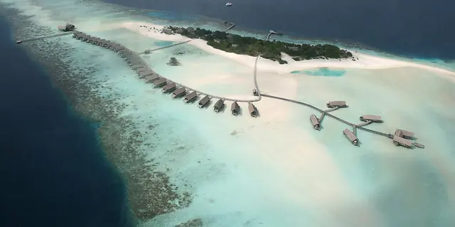 Aerial view of a small Maldives island ringed by a coral reef